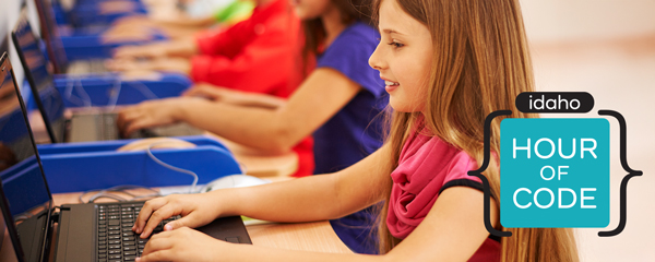 Student smiling while working on a laptop, with an Idaho Hour of Code logo in the bottom right corner